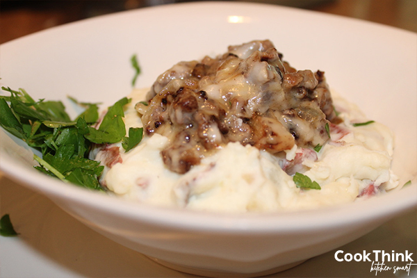 mashed potato stroganoff in a bowl, topped with fresh chopped parsley