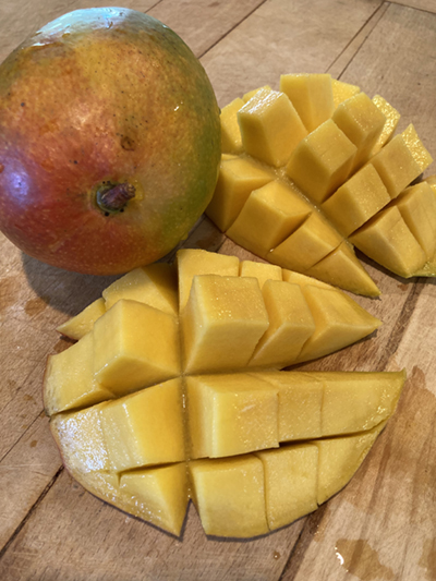 cut mango next to a whole mango