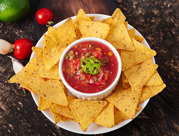 Mexican nacho chips and salsa dip in bowl on wooden background, food that starts with x