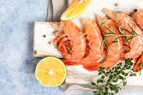 raw shrimp on wooden cutting board with lemon and herbs