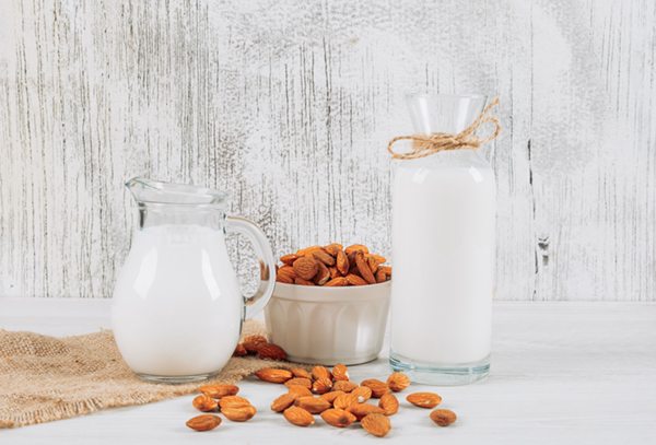 almond milk in a carafe with almonds in a bowl