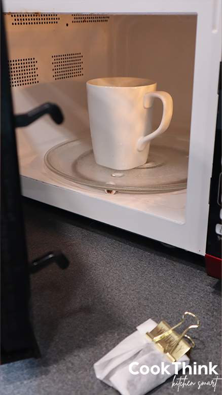 hot cup of water in the microwave with folded coffee bag